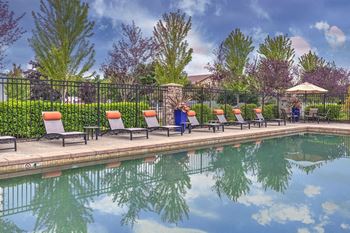 a pool with lounge chairs and umbrella at the west end lodge apartments in beaumont